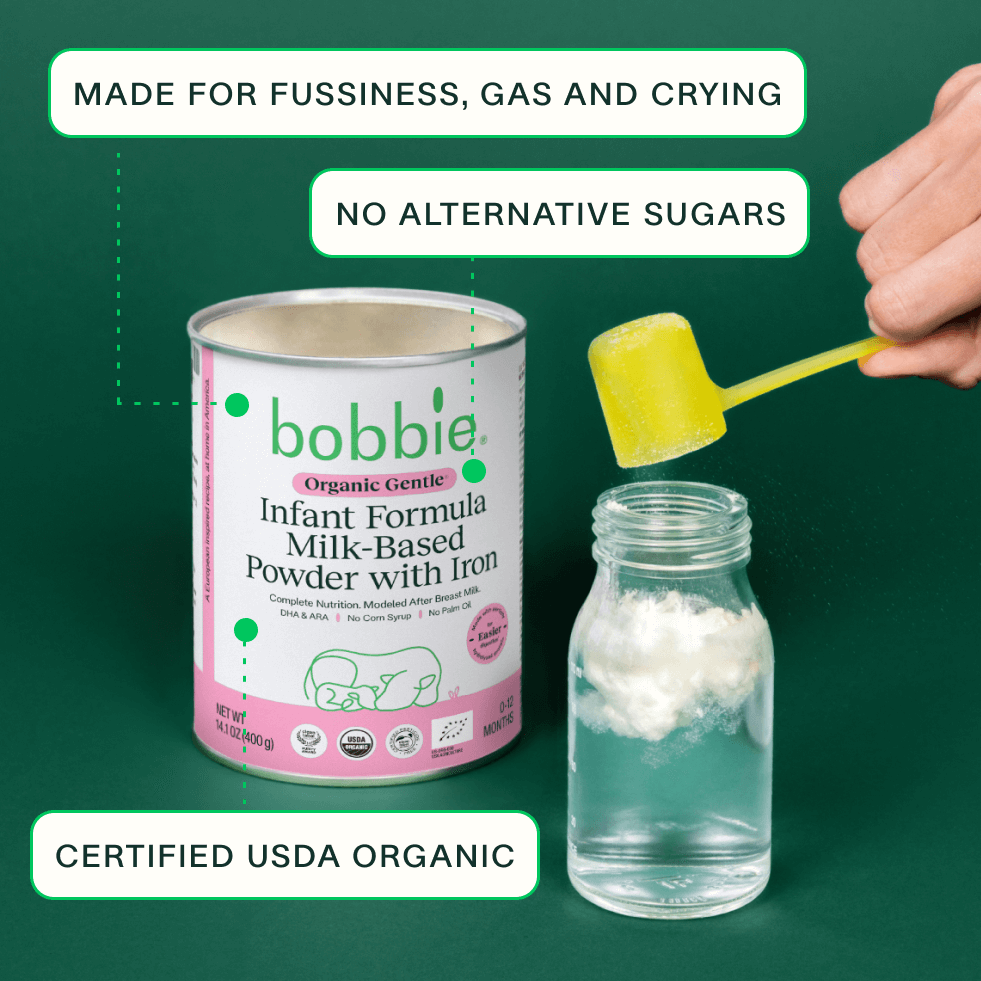 Bobbie Organic Gentle Infant Formula powder being measured into a glass bottle.