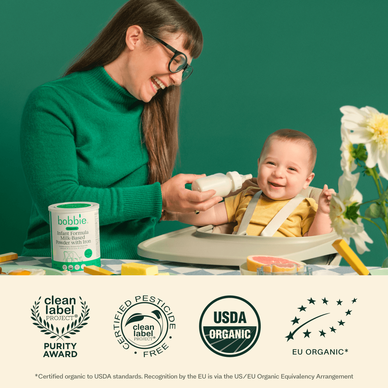 Woman feeding a baby in a high chair with organic infant formula product displayed.