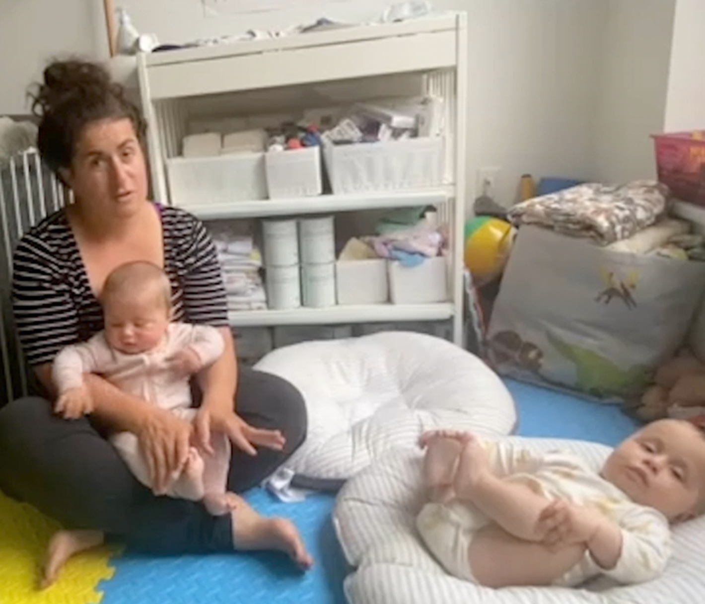 Mom sits cross legged on the floor with six month old twins