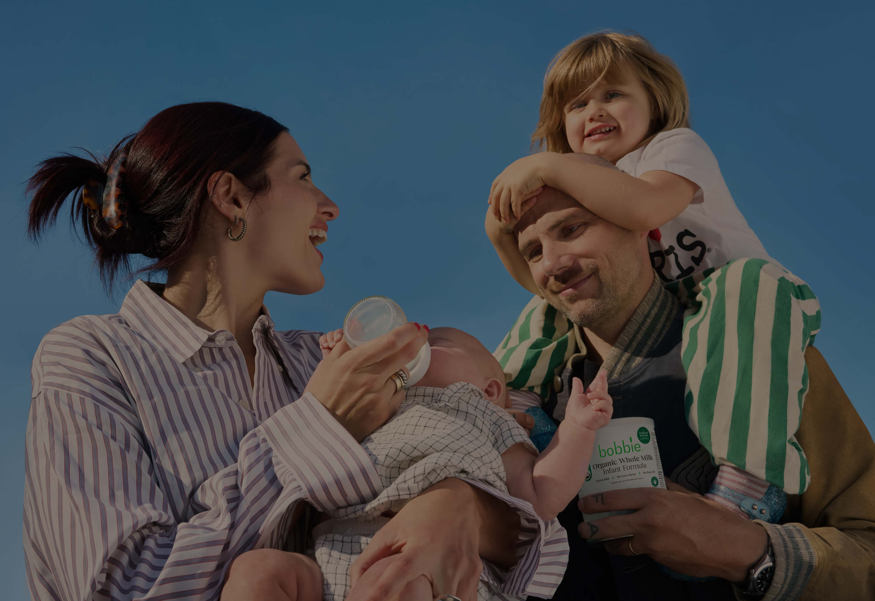 Family of four outdoors with a clear blue sky