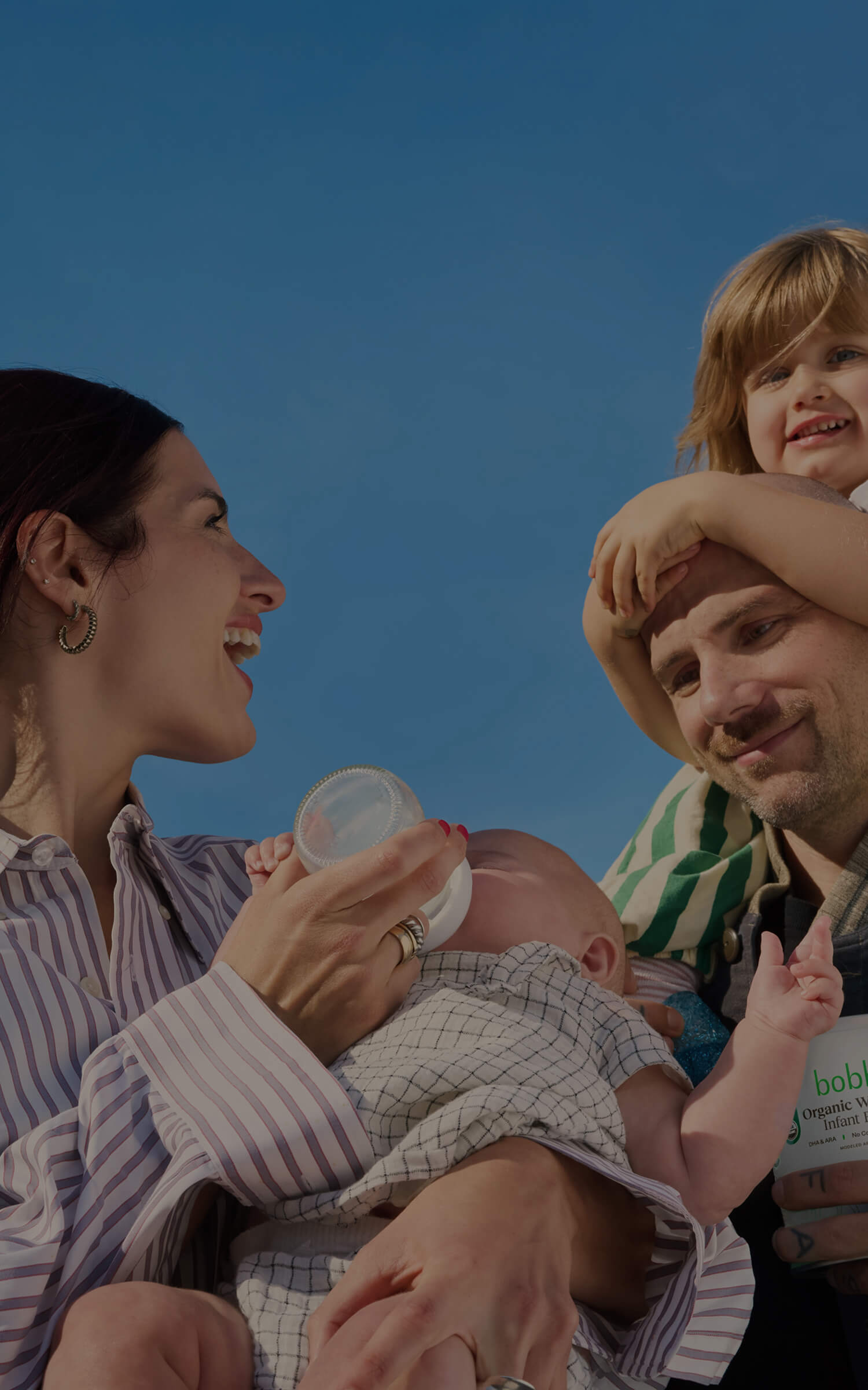 Family with a baby and toddler against a blue sky