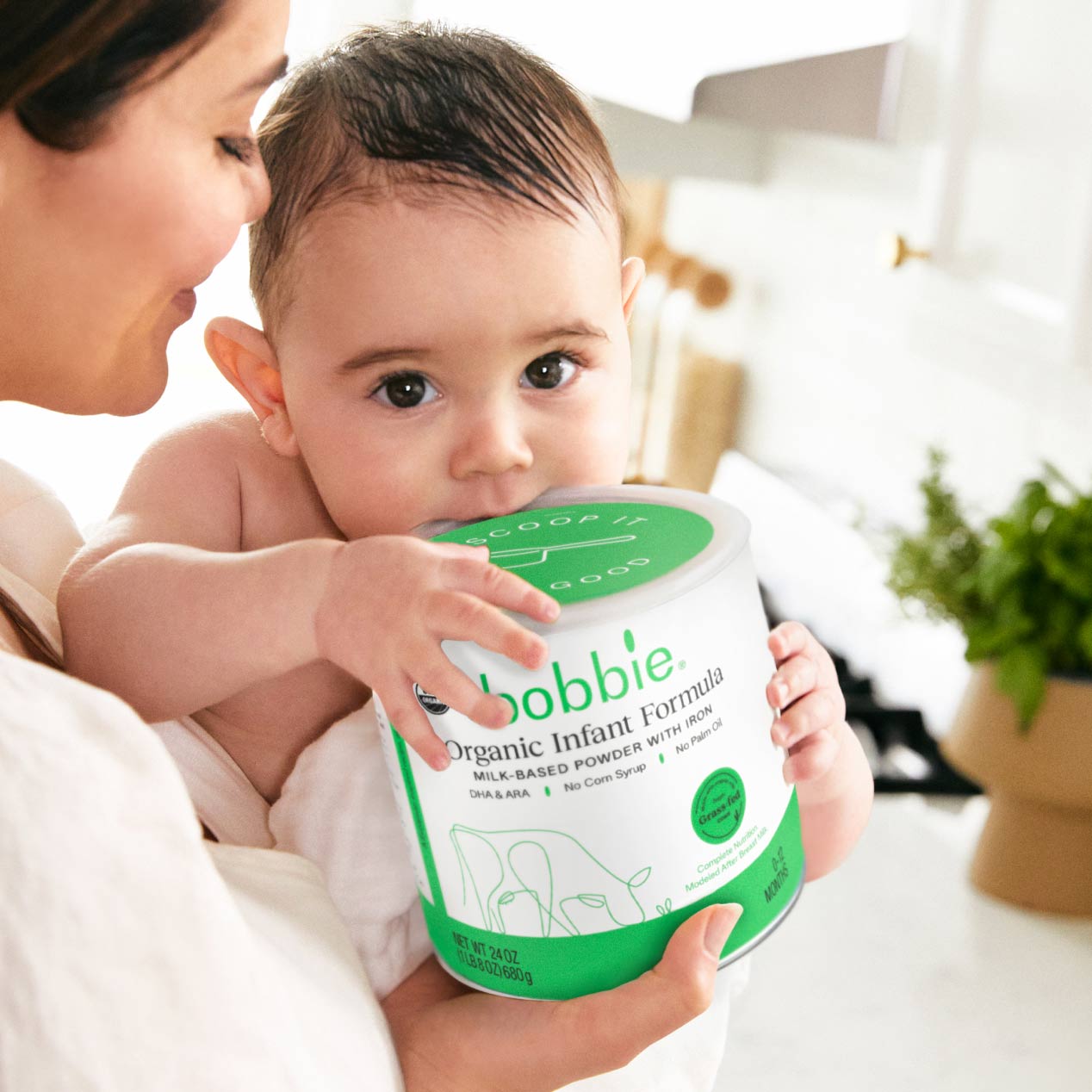 Lifestyle image of a baby holding onto a can of Organic Infant Formula